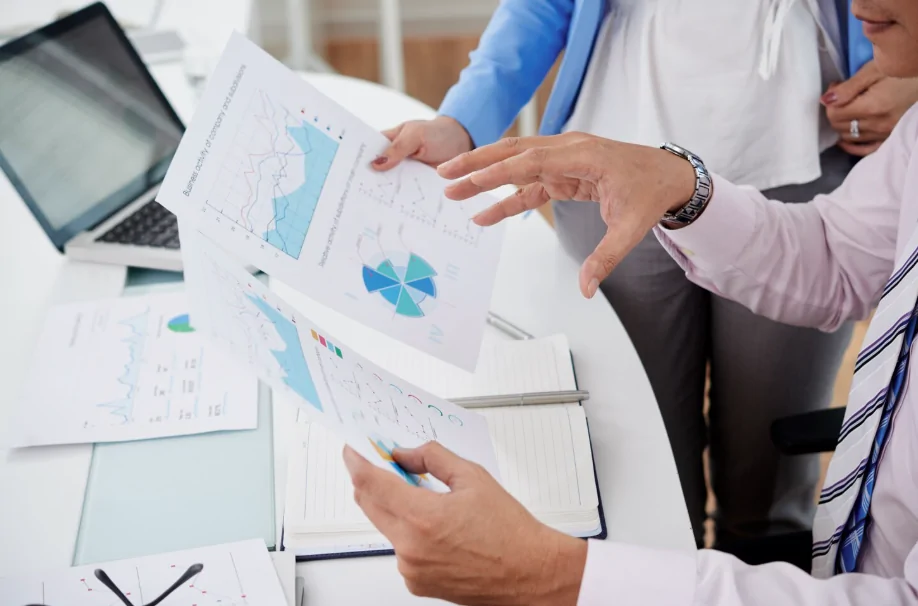 Profissionais da área da saúde analisam gráficos e relatórios financeiros em reunião sobre gestão e tecnologia no setor médico.